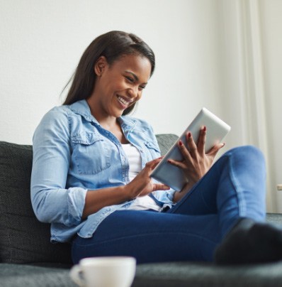 Smiling woman reading on tablet while sitting on couch