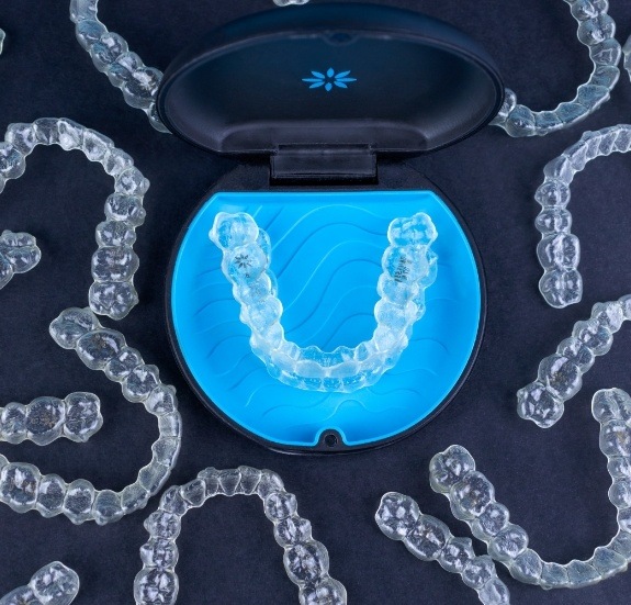 Several Invisalign aligners on table with one in an aligner carrying case