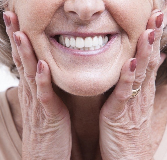 Close up of smiling senior woman touching her face