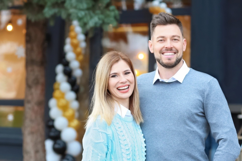 Man and woman in sweaters smiling after dental services in Revere