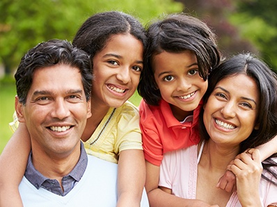 Family of four smiling in grassy field