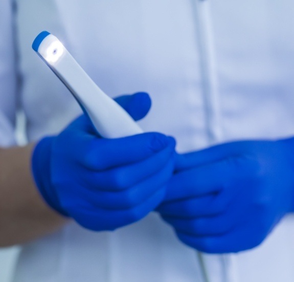 Dental team member holding a thin white intraoral camera