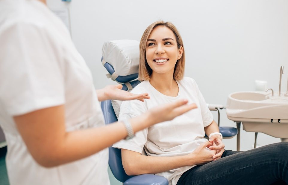 Woman in dental chair smiling while talking to emergency dentist in Revere