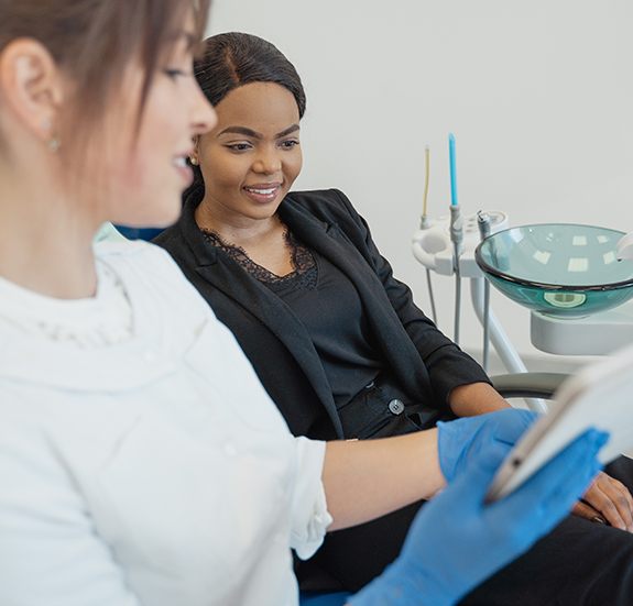 Dental team member showing a patient a tablet during dental checkup