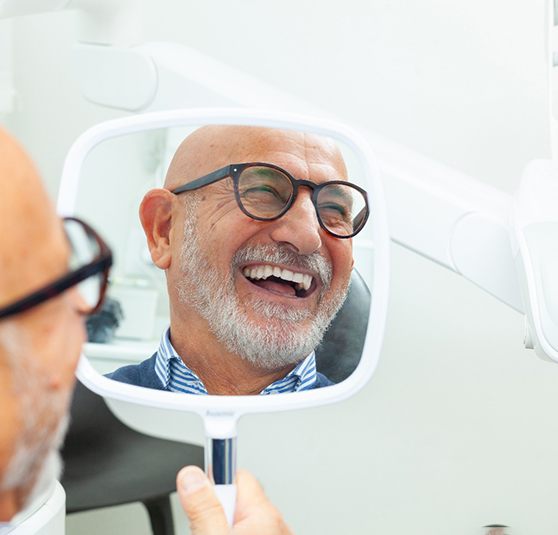 Older man smiling with his new set of full arch implant restorations