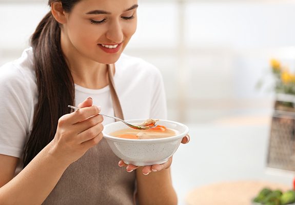 A woman eating a warm bowl of soup