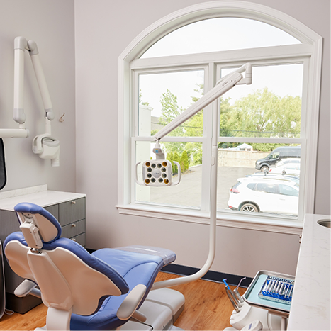 Dental treatment room with window showing trees and parking lot