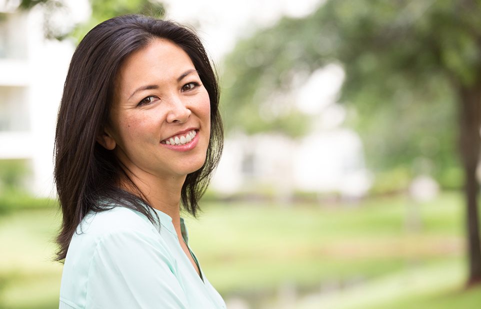 Woman smiling outdoors after restorative dentistry in Revere